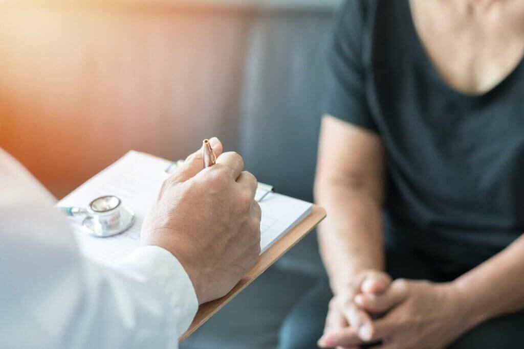 Médecin prenant des notes avec sa cliente dans le fond