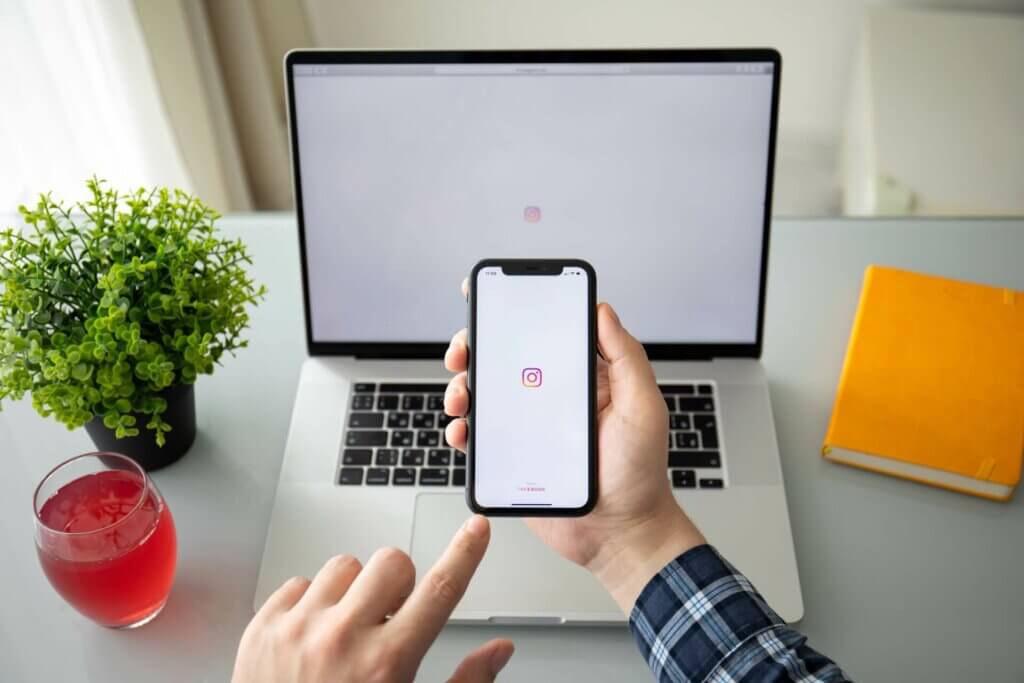 Personne tenant son portable devant son ordinateur portable