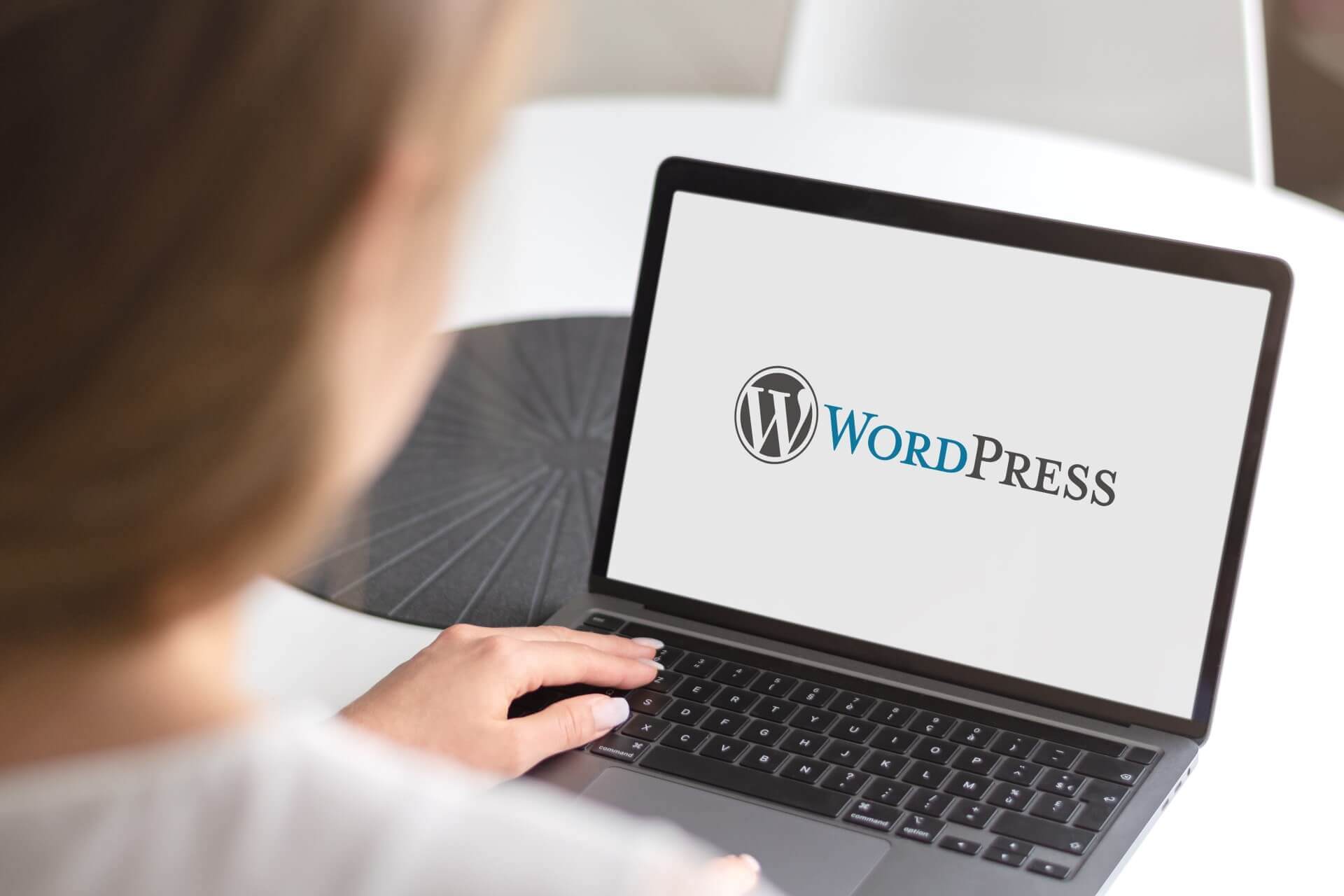 Personne utilisant son ordinateur portable avec le logo WordPress en fond